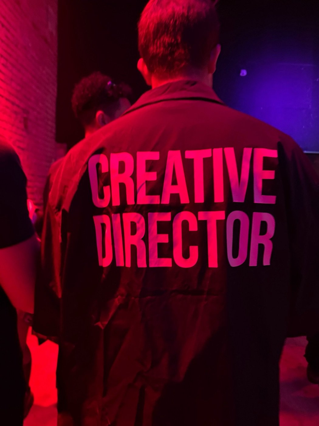 Creative director jacket under neon event lighting